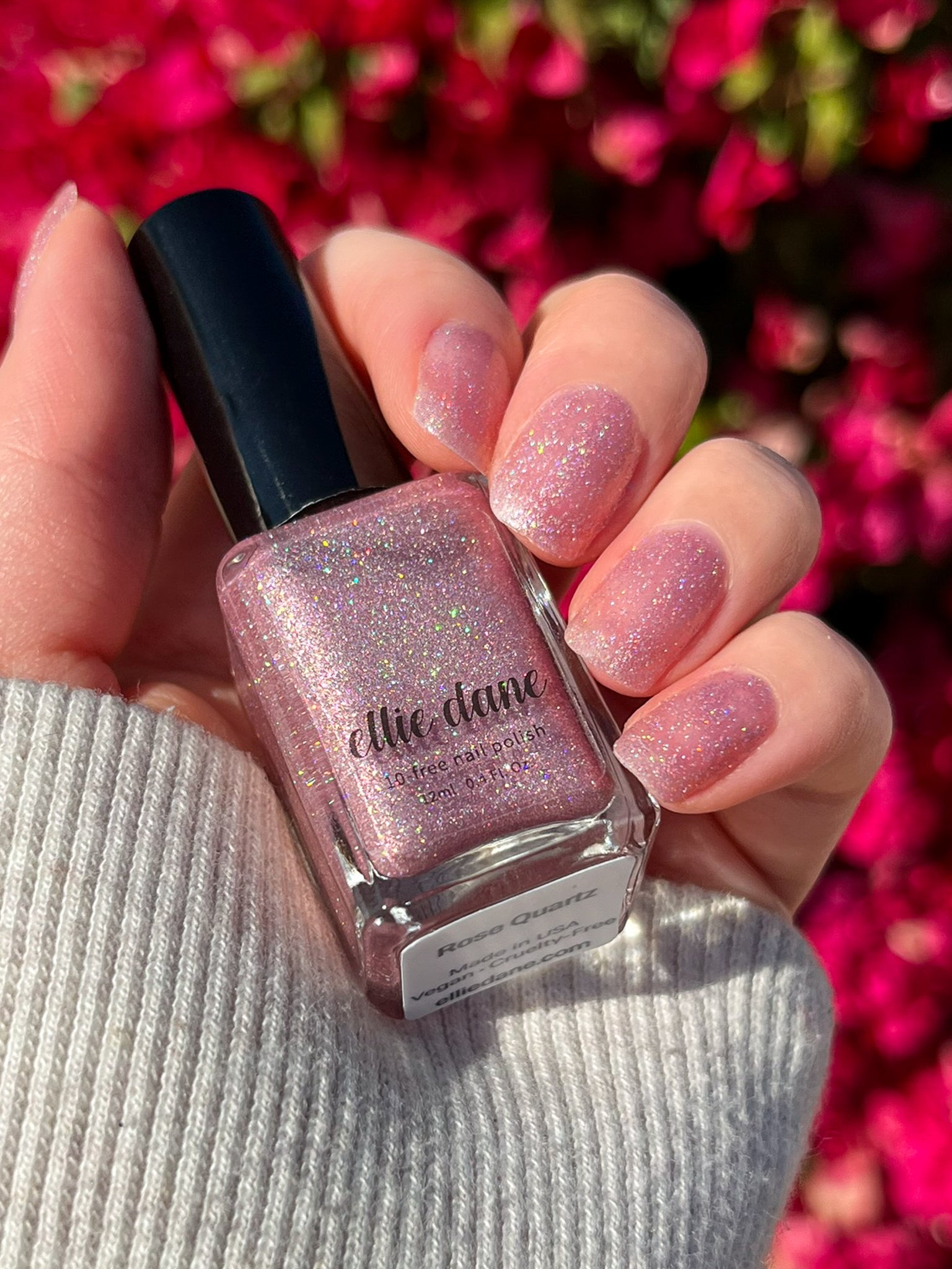 Rose Quartz nail polish swatched on nails holding bottle in sunlight